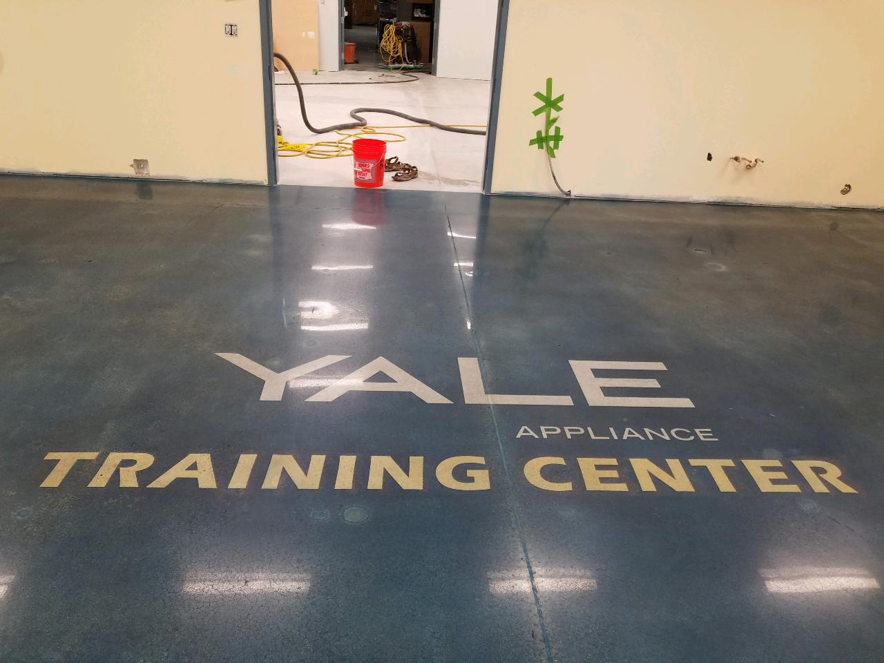 A black polished concrete floor with the logo of the Yale Training Center stained into the surface